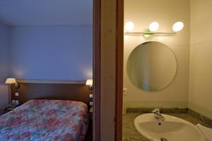 uma casa de banho com um lavatório, um espelho e uma cama em Logis Hotel Restaurant Le Cygne em Yssingeaux