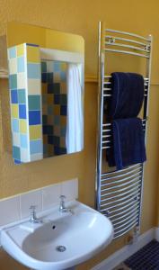 een badkamer met een wastafel, een spiegel en blauwe handdoeken bij Kinneil Self Catering in Lamlash
