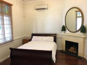a bedroom with a bed with a mirror and a fireplace at Charming Federation style home minutes from CBD in Perth