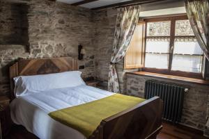 1 dormitorio con cama y pared de piedra en Alén do Mis - Hotel Rural, en Foz