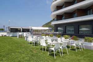 
a patio area with chairs, tables, chairs and umbrellas at Hotel & Thalasso Villa Antilla - Habitaciones con Terraza - Thalasso incluida in Orio
