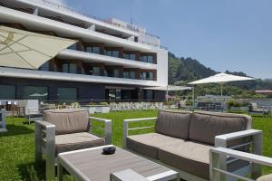 a patio with a couch and chairs and a building at Hotel & Thalasso Villa Antilla - Habitaciones con Terraza - Thalasso incluida in Orio +49 photos