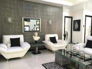 a living room with white chairs and a glass table at B201 Low Rise Condo in Manila