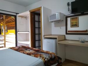 a small room with a bed and a microwave at RC Sol de Boicuçanga - Chalés in Boicucanga