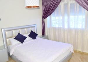 - une chambre dotée d'un lit blanc avec des oreillers bleus et d'une fenêtre dans l'établissement The happy lounge, à Nador