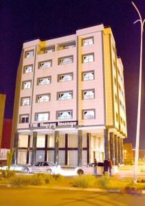 un grand bâtiment avec des voitures garées devant lui dans l'établissement The happy lounge, à Nador