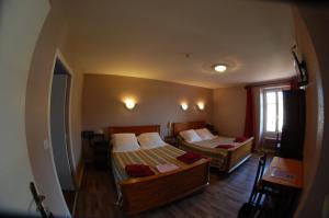 a hotel room with two beds and a window at La Vieille Auberge in Saint-Privat-dʼAllier