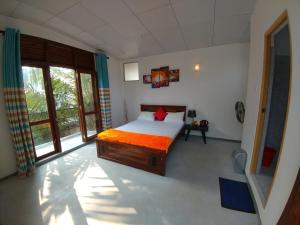 ein Schlafzimmer mit einem Bett in einem Zimmer mit Fenstern in der Unterkunft Sun Hill Home in Weligama