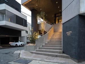 a staircase leading to a building with a white car at Resters Bed&Co. in Kumamoto
