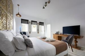 a bedroom with a bed and a desk with a television at Mythos Palace Resort & Spa in Georgioupolis +161 photos