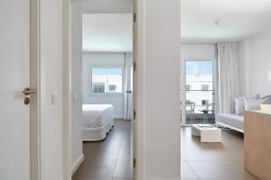 a hotel room with a white bed and white walls at Ibiza Sun Apartments in Playa d'en Bossa