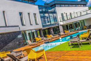 un edificio con una piscina con sillas amarillas en Open Hotel Szentes en Szentes