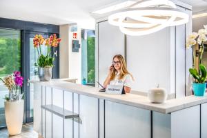 a woman sitting at a counter talking on a phone at Open Hotel Szentes in Szentes