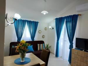 uma sala de estar com cortinas azuis e uma mesa com flores em Apartman Pink em Tivat