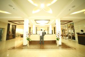 Ein Mann steht an einem Tresen in einer Lobby. in der Unterkunft Hotel Indraprasttha in Vijayawāda