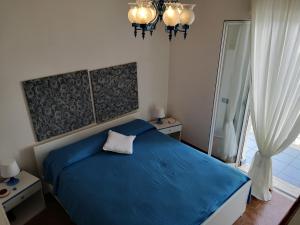 una camera con letto blu e lampadario a braccio di Taormina Rising Sun Apt a Forza dʼAgro