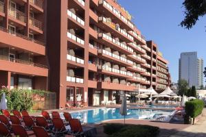 ein Hotel mit Stühlen und einem Schwimmbad vor einem Gebäude in der Unterkunft Gladiola 3-star in Goldstrand