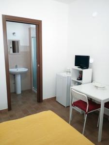 Cette chambre comprend une table et une salle de bains pourvue d'un lavabo. dans l'établissement Vittoria Resort Residence-B&B, à Galatina