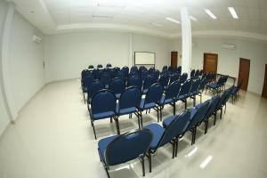 an empty room with blue chairs in a classroom at Hotel Santa Maria in Campo Mourão