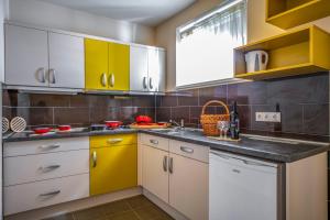 una cocina con armarios amarillos y blancos y fregadero en Termál Kemping Apartmanok és Bungalók en Harkány