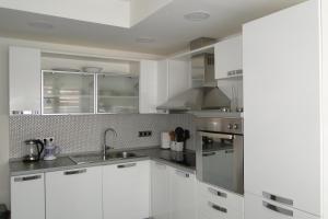 a white kitchen with white cabinets and a sink at Apartment Galerija in Tuzla