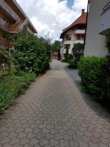 a cobblestone path between two buildings and a building at Napsugár Apartman in Balatonlelle