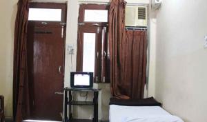 a small room with a bed and a television at Hotel Vardaan in Kankhal