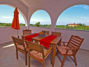comedor con mesa, sillas y sombrilla en Apartments Aleksandra 1132, en Peroj