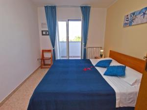 a bedroom with a large bed with a blue blanket at Apartments Aleksandra 1132 in Peroj