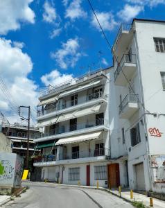a white building with balconies on a street at Sunny apartment near the center in Thessaloniki
