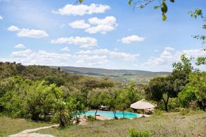 a swimming pool in a field with an umbrella at Entumoto Toto Camp in Ololaimutiek