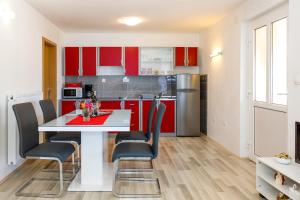 a kitchen with red cabinets and a white table and chairs at Apartman Dobrila in Vrh