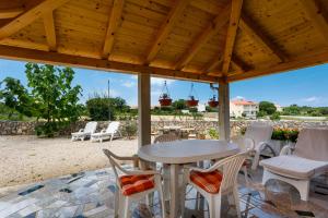 a patio with a table and chairs under a wooden roof at Apartman Dobrila in Vrh