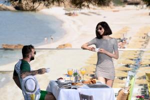 a man and a woman sitting at a table at the beach at Alexandra Beach Spa Resort in Potos