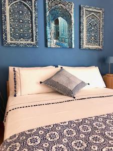 a bed with two framed pictures on a blue wall at Casa Del Sole B&B in Tropea