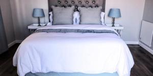 een slaapkamer met een groot wit bed met 2 lampen bij Clarens Escape in Clarens