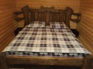 a wooden bed with plaid pillows in a room at Anastasiya in Izki