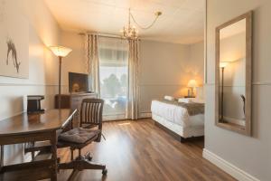 a bedroom with a desk and a bed and a mirror at Auberge des Berges in Saint-Félicien