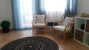 a living room with two chairs and a rug at Apartamento Estúdio Pinhalmar in Vila Nova de Milfontes