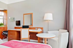 a room with a desk and a table with a mirror at Italiana Hotels Florence in Florence