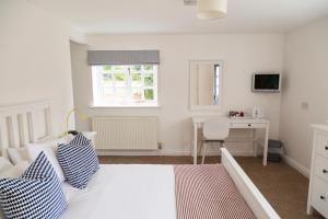 a white bedroom with a bed and a desk at Five Bells Inn, Wrentham in Wrentham