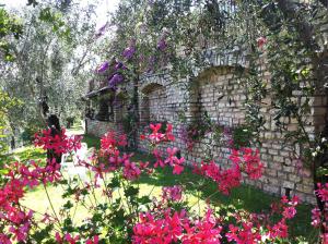 a garden with pink flowers in front of a stone building at Hotel Villa Margherita in Limone sul Garda