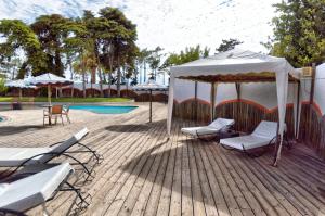 a deck with chairs and a tent next to a pool at Hotel Vale Da Telha in Aljezur
