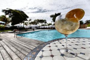 a glass of wine sitting on a table next to a pool at Hotel Vale Da Telha in Aljezur