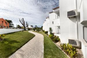 a walkway between two white buildings at Hotel Vale Da Telha in Aljezur