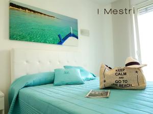 a bed with blue pillows and a picture of the ocean at I MESTRI Holiday Homes in Uggiano la Chiesa