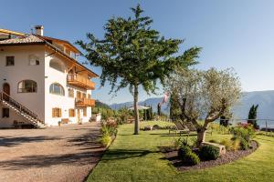 a building with a tree next to a park at Mederle Hof in Appiano sulla Strada del Vino