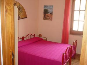 a bedroom with a pink bed and a window at Villetta a 300mt dal mare Cala Sinzias in Cala Sinzias