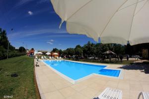 a large swimming pool with an umbrella and chairs at Agriturismo Al Buttasella in Lavariano