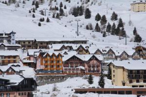 une ville recouverte de neige avec des bâtiments dans l'établissement Hotel Residence Dahu, à Passo del Tonale